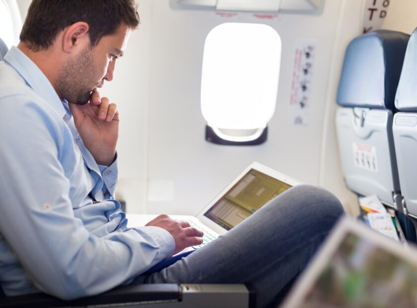 Businessman working with laptop on airplane.