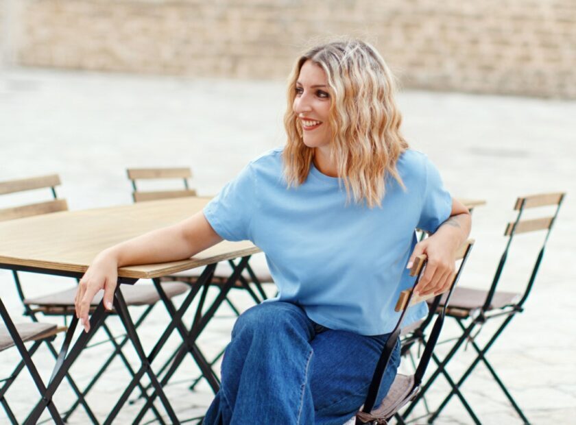 Young women wearing t-shirt and jeans sits in a street cafe