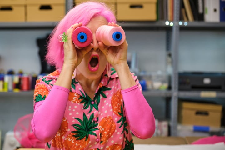 Seamstress with colorfull clothes making funny faces with sewing thread reels.