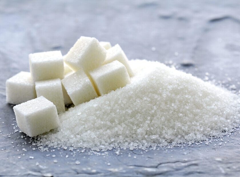white granulated sugar and refined sugar on a gray background